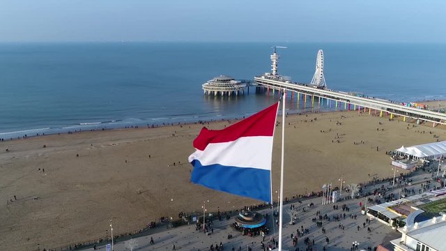 Aerial view of flag of the Netherlands is a horizontal tricolour of red white and blue also showing the Dutch coastline with beach pier and ferris wheel in background located in The Hague 4k quality
