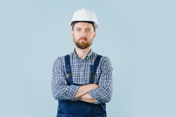 Confident construction worker in a white helmet and blue overalls