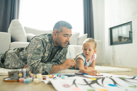 Military man painting family tree with his cute daughter