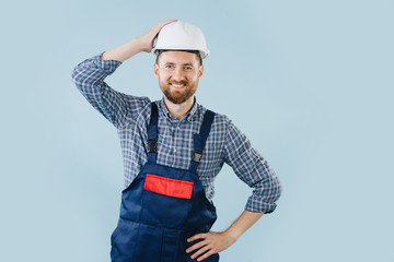 Confident construction worker in a white helmet and blue overalls