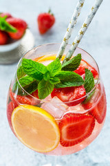 Pink gin and tonic cocktail with prosecco and strawberries, garnished with fresh mint - refreshing summer alcoholic drink