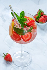 Pink gin and tonic cocktail with prosecco and strawberries, garnished with fresh mint - refreshing summer alcoholic drink