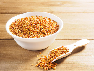 Fenugreek (Trigonella) in a ceramic white cup with scoop on a wooden background