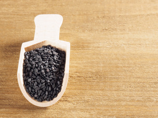 Black sesame (Sesamum indicum) in a scoop on a wooden background