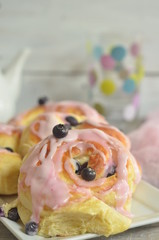 Buns with cheese and blueberries with icing on a wooden background