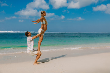 Fototapeta na wymiar Pregnant woman with husband expecting baby with yoga pose at beach