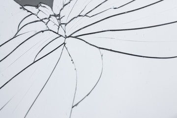 Broken mirror with fragments and cracks close-up.