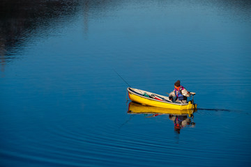 青色の湖と黄色いボートに乗った人物（A person on a blue lake and a yellow boat）