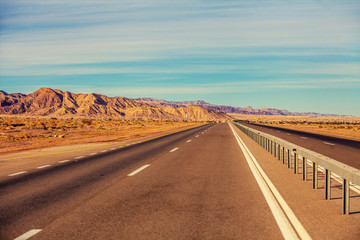 Driving a car on the mountain road in Israel. Desert landscape. Empty road. View from the car of mountain landscape with the striped sky. Israel