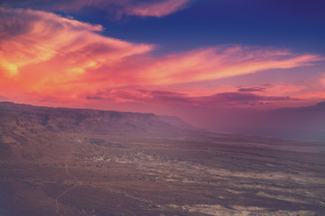 Mountain desert landscape. View of the valley from the mount. Desert in the early morning. Beautiful sunrise over Masada with dramatic sky. The Judaean Desert. Landscape in Dead sea region