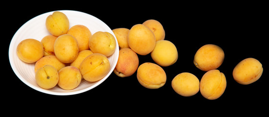 Ripe apricot in a white plate on a black background