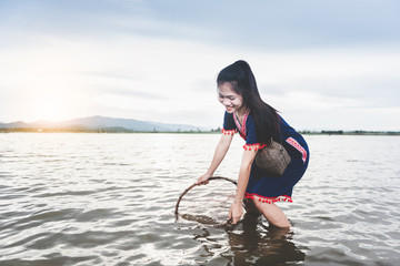 Beautiful Asian girls fishing in the lake with fish trap. Life style of people in countryside of Thailand