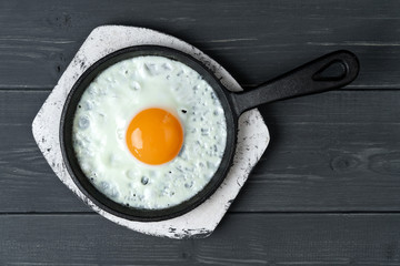 fried eggs in cast iron pan on white wooden stand.