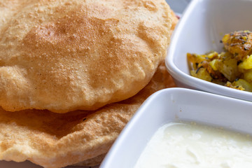 Puri Bhaji, Masala Aloo Sabzi fry served with fried puri or Indian bread and curd, selective focus.