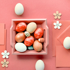 Easter flat lay in coral color with painted eggs, cards, envelopes and decorative flowers
