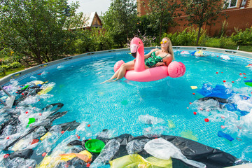 Problem of trash, plastic recycling, pollution and environmental concept - silly woman swims and have fun in a polluted pool. Bottles and plastic bags float near her