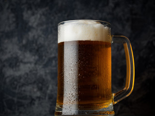 A mug of light beer on a dark concrete background