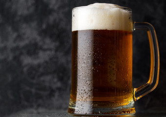 A mug of light beer on a dark concrete background