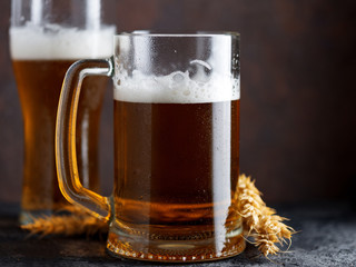 A mug of beer and a beer glass on a dark background . Wheat German beer. Oktoberfest. dark brown Copyspace background