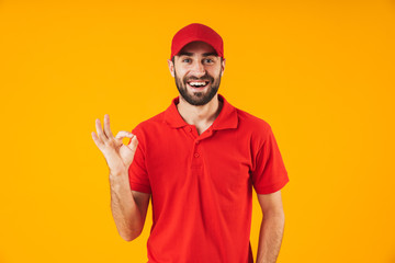 Portrait of happy delivery man in red t-shirt and cap smiling and showing ok sign