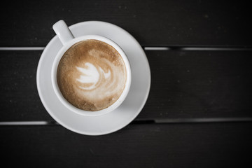 Cup of coffee with milk on dark wooden table