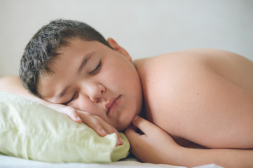 cute fat little caucasian kid lying in bed on pillow deep sleeping daytime