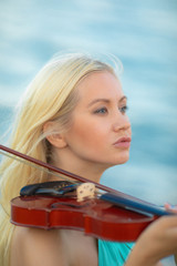 Girl on the beach plays the violin.
