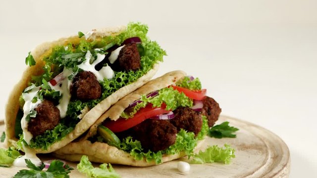 Kebab, kofta in pita, bun. Traditional southern European dish. Front view.  Turning the platter. Slow motion. 