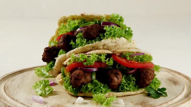 Kebab, kofta in pita, bun. Traditional southern European dish. Front view.  Turning the platter. Slow motion.