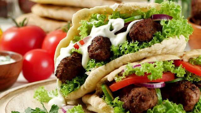 Kebab, kofta in pita, bun. Traditional southern European dish. Front view.  Turning the platter.