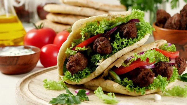 Kebab, kofta in pita, bun. Traditional southern European dish. Front view.  Turning the platter.