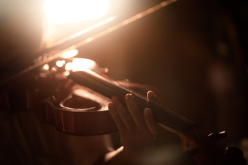 Close-up shot little girl playing violin orchestra instrumental with warm tone and lighting effect...