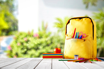 Table background and a schoolbag with some colorful school supplies. Empty space for advertising...