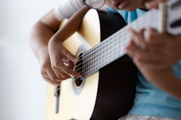 Fototapeta premium Mother teaching the daughter learning how to play acoustic classic guitar for jazz and easy listening song select focus shallow depth of field