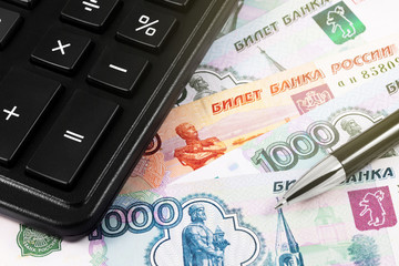 finance concept in closeup calculator and pen on the Russian money, rubles banknotes background