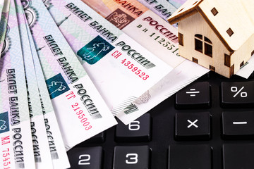 finance concept in closeup house symbol and calculator with Russian money, rubles banknotes background