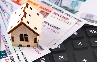 finance concept in house symbol and black calculator with Russian money, rubles banknotes background closeup