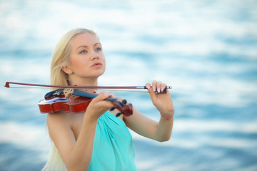 Girl on the beach plays the violin.