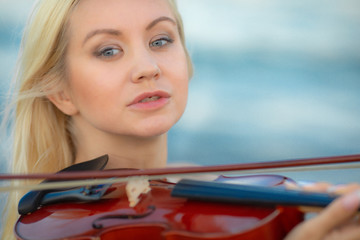 Girl on the beach plays the violin.