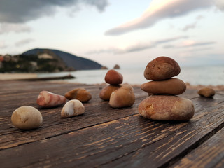 Balanced red rocks on the background of a sea landscape, on a wooden flooring, pebble pyramid. Concept of balance, harmony and meditation. Soft focus, selective focus