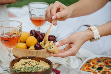 Woman hand smearing hummus on bread with a spoon.