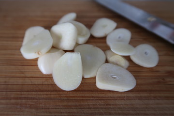 Peeled fresh garlic on a wooden chopping board as an ingredient for Thai cuisine