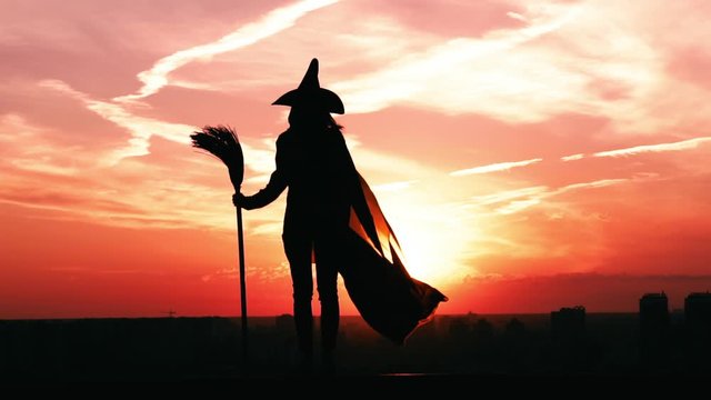 back view witch with fluttering cloak cityscape slow motion city view sky at sunrise halloween concept
