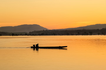 Fototapeta na wymiar River view morning of a small fishing boat running in Mekong river with yellow sun light background, sunrise at Khong Chiam, Ubon Ratchathani, north-eastern of Thailand.