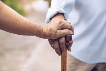 Close up of elderly hands in wrinkles holding walking stick.elderly old man with walking stick...