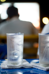 Glass of drinking ice water with ice cube placed on table
