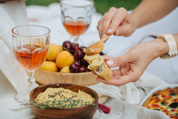 Woman hand smearing hummus on bread with a spoon.