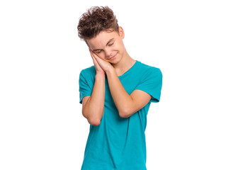 Portrait of teen boy sleeping tired or dreaming posing with hands together while smiling with closed eyes. Cute young caucasian teenager isolated on white background. Happy child wearing blue t-shirt