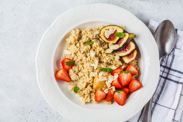 Quinoa breakfast porridge with strawberries and figs in white plate. Healthy breakfast concept.
