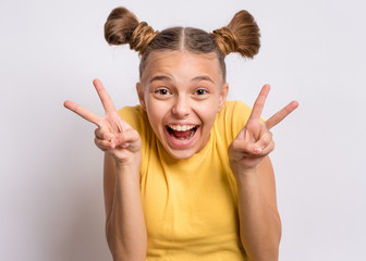 Portrait of successful teen girl winner making Victory Gesture, on gray background. Beautiful...